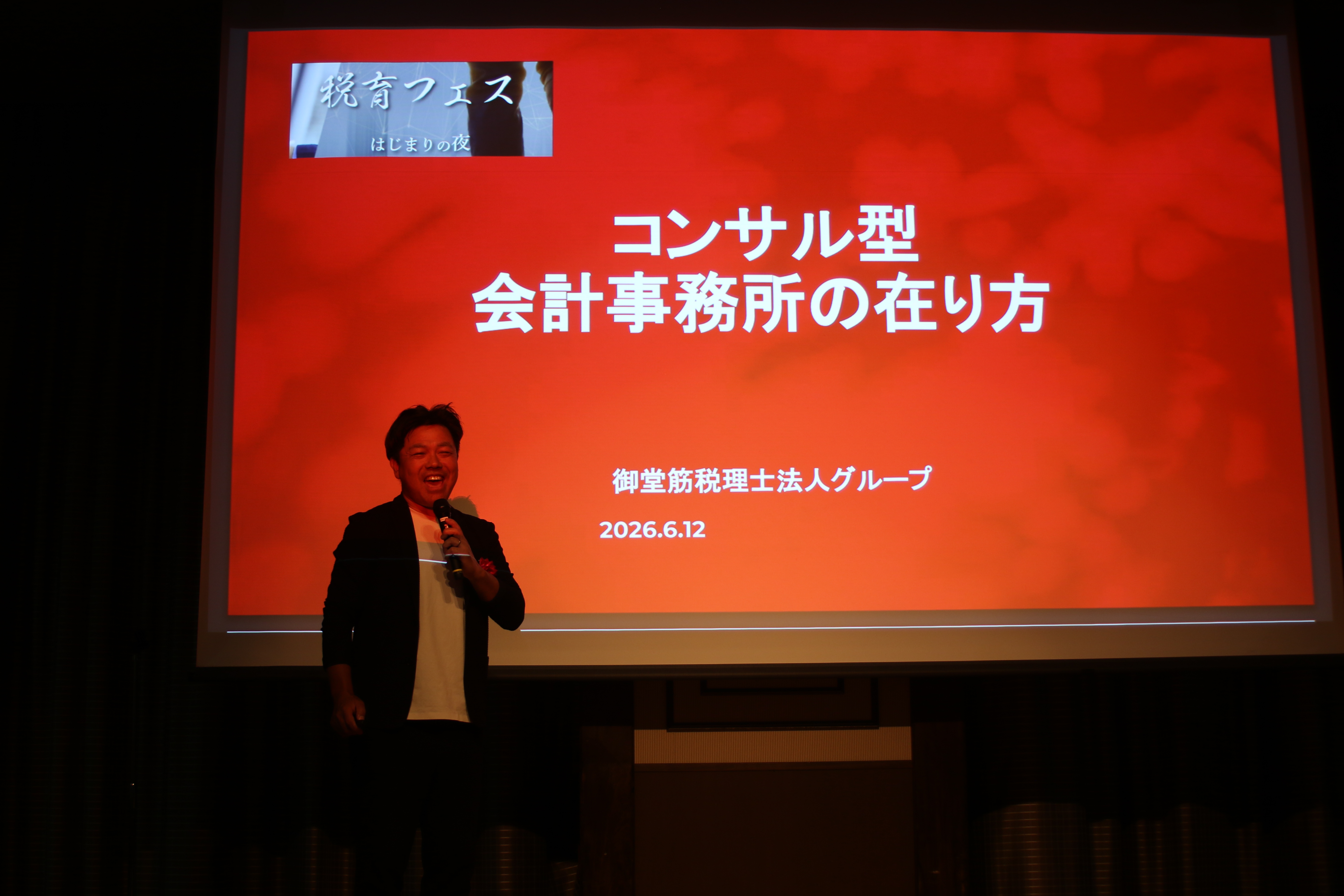 赤いスクリーンを背に登壇する税育フェス2026の登壇者